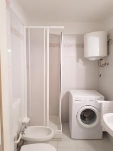 a white bathroom with a washing machine and a sink at Fulvia's cozy apartment with terrace in Monterosso al Mare