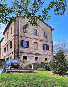 a large brick building with a car parked in front of it at La Cascina di Muttley in Doglio