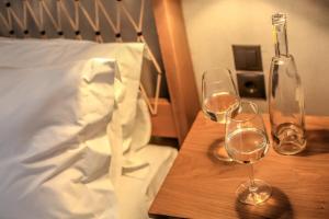 dois copos de vinho numa mesa de madeira ao lado de uma cama em Meteora Heaven and Earth Kastraki premium suites - Adults Friendly em Kalabaka