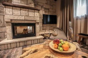 a table with a plate of fruit and two glasses of wine at Meteora Heaven and Earth Kastraki premium suites - Adults Friendly in Kalabaka