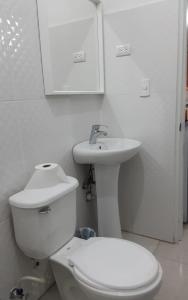 Baño blanco con aseo y lavamanos en Villa colonial suite n 4 basic interior en Río San Juan