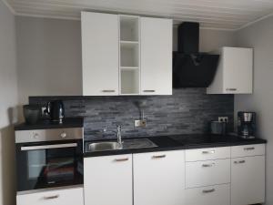 uma cozinha com armários brancos e um lavatório em Ferienwohnung Eifelbrise em Nideggen