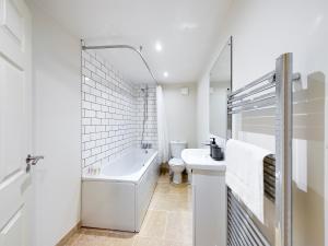 a bathroom with a tub and a toilet and a sink at Redhill town centre apartment by Livingo in Redhill