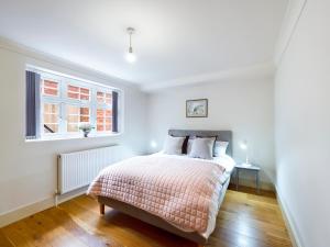 a white bedroom with a bed and a window at Redhill town centre apartment by Livingo in Redhill