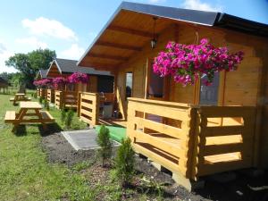 a wooden cabin with pink flowers hanging from it at DOMKI POD DĘBEM in Grzybowo