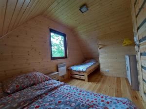 a room with a bed and a window in a log cabin at POD FALAMI - domki letniskowe in Polańczyk