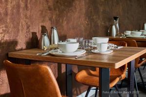 a wooden table with plates and bowls on it at Hotel aanders in Neumünster