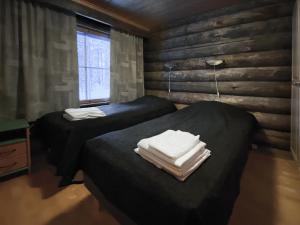 two beds in a room with wooden walls at Economy Lomailevi in Levi