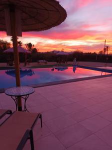 einen Sonnenuntergang über einem Pool mit einem Tisch und einem Sonnenschirm in der Unterkunft casadelfenix in Alicante
