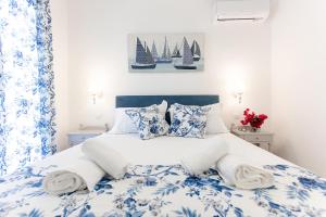 oliva e mare luxury suite في مدينة كورفو: غرفة نوم بسرير ازرق وبيض مع وجود أشرعة على الحائط