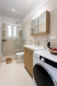 oliva e mare luxury suite في مدينة كورفو: حمام مع مغسلة وغسالة ملابس