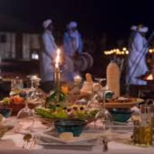 a table with food and wine bottles and people in the background at Royal Luxury Cafe Du Sud in Merzouga +24 photos