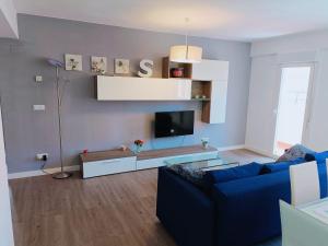 sala de estar con sofá azul y TV en Apartamento El Torreón, con opción a parking, en Zaragoza
