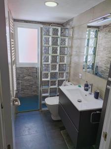 a bathroom with a sink and a toilet and a window at Apartamento El Torreón, con opción a parking in Zaragoza