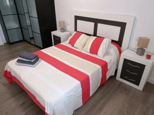 a bedroom with a large bed with red and white stripes at Apartamento El Torreón, con opción a parking in Zaragoza
