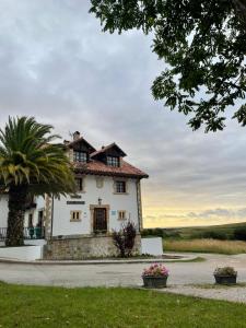 uma grande casa branca com uma palmeira em frente em Don Pablo em Pechón