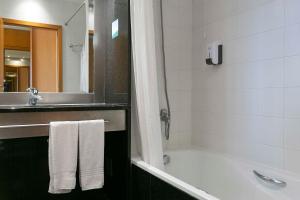 a bathroom with a shower, sink, and toilet at Hotel Colombo in Vila do Porto