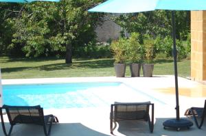 a swimming pool with two chairs and an umbrella at Gite Eynardou in Naussannes
