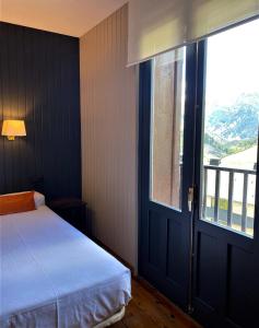 1 dormitorio con cama y ventana grande en Hotel Tobazo, en Candanchú