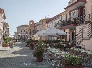 une rue vide avec des tables et des chaises avec un parasol dans l'établissement Residence Le Pavoncelle, à Santa Teresa Gallura