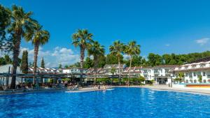 a large swimming pool in a resort with palm trees at Lykia Botanika Beach Fun & Club - All Inclusive in Fethiye
