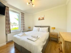 Schlafzimmer mit einem großen weißen Bett und einem Fenster in der Unterkunft Clyde Villa in Glasgow
