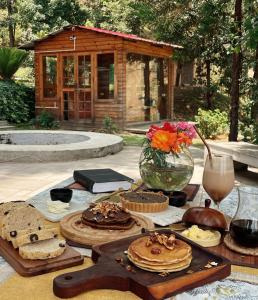 a table with bread and cakes and a vase of flowers at Shantiniketan Mountain Home in Almora