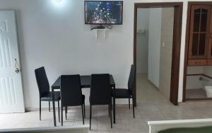 uma mesa de jantar com cadeiras pretas e uma televisão em Villa Colonial Suite 5, Familiar Plus. em Río San Juan