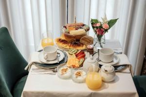 una mesa con una bandeja de alimentos para el desayuno y zumo de naranja en Trovador Guest House, en Guimarães
