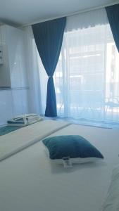 a white bed with a blue pillow and a window at Garsoniera Camy in Saturn
