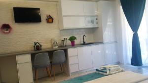 a kitchen with white cabinets and a counter with two chairs at Garsoniera Camy in Saturn