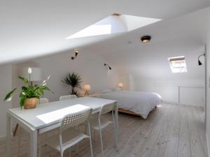 a white bedroom with a bed and a table and chairs at GiG Capsule Hostel in Ericeira