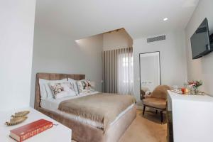 a bedroom with a bed and a tv and a chair at Trovador Guest House in Guimarães +75 photos