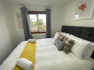 een groot wit bed met een gele deken en kussens bij Pure Apartments Fife - Dunfermline - Pitcorthie in Dunfermline