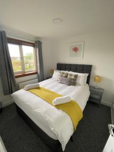 Pure Apartments Fife - Dunfermline - Pitcorthie في دنفرملاين: غرفة نوم مع سرير أبيض كبير مع نافذة