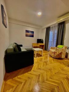 a living room with a black couch and a wooden floor at DARTAD APARTMENT in Ohrid