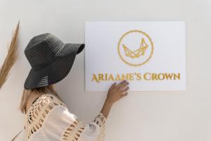 Ariadne's Crown Suites Astro Concept Luxury في Vívlos: امرأة في قبعة تحمل علامة على الحائط
