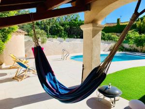 a hammock on a patio next to a pool at Villa piscine 8 pers à pied 15mn plage et 30mn JO in Marseille