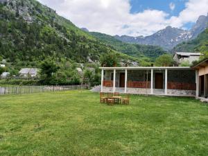 a house in a field with mountains in the background at Buni Shqipes in Theth