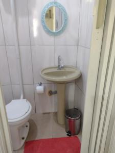 a bathroom with a sink and a toilet and a mirror at Casa da Praia in Santos