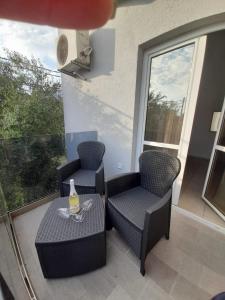 a balcony with two chairs and a table with a bottle on it at Black & White in Sutomore