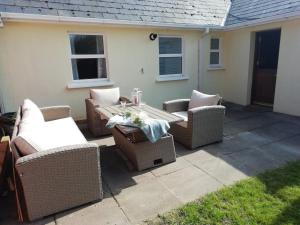 a group of wicker chairs and a table on a patio at Bovinda Cottage - By the Beach, Bettystown in Bettystown