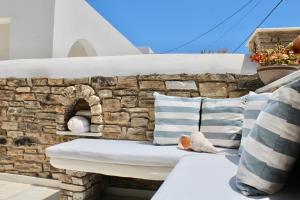 a bench with pillows and a brick wall at Aegeo Inn in Antiparos