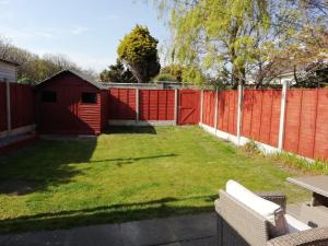 a backyard with a red fence and a grass yard at Bovinda Cottage - By the Beach, Bettystown in Bettystown