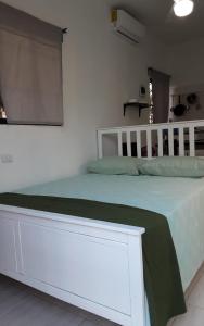 a bedroom with a white bed with a green blanket at Vilaa Colonial Suite N 7, Basic exterior in Río San Juan