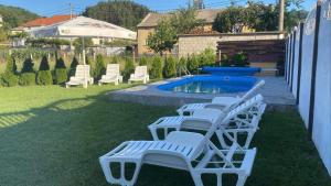 a group of white lounge chairs and a pool at Бялата Къща in Chakalarovo