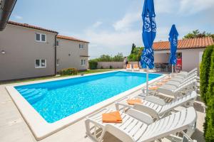 uma piscina com espreguiçadeiras e guarda-sóis em Ferienhaus Brcina em Pula