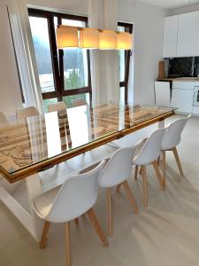 une salle à manger avec une table en verre et des chaises blanches dans l'établissement Baltica Heaven - Apartament dwupoziomowy przy plaży, à Rogowo