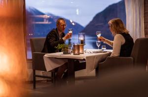 un hombre y una mujer sentados en una mesa bebiendo vino en Dragsvik Fjordhotel en Balestrand