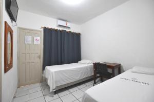 a bedroom with two beds and a blue curtain at Hotel Tapajós in Cuiabá